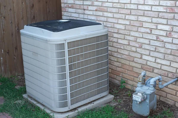 Technician inspecting outdoor ac condenser in a baltimore rowhome backyard